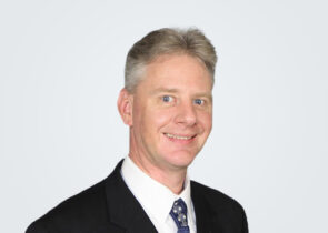 Headshot of Jeremie Maehr, a man with blond-grey hair, in front of a light grey background.