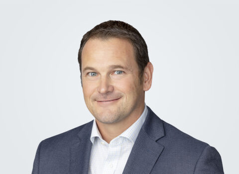 Headshot of Scott Larew, a man with brown hair, in front of a light grey background.