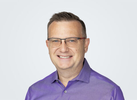 Headshot of David Stout, a man brown hair and glasses, in front of a light grey background.