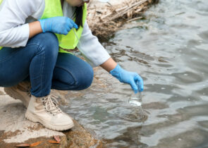 Female environmentalist hands in glove collects water samples from a river to explore and testing for infections. Water and ecology concept