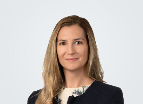 Headshot of Sarah King, a person with dark blond hair, wearing a black blazer and floral shirt.